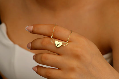 Gold necklace with a heart-shaped pendant featuring a 'P' on a hand.