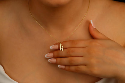 A close-up image of a woman wearing a sterling silver necklace with a gothic style initial pendant.