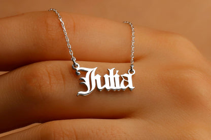 A silver necklace with a dainty gold-colored chain and a custom name pendant in a cursive script.