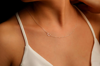 A close-up image of a custom Sideway Initial Necklace worn on a person's neck, displaying silver letter on a chain.