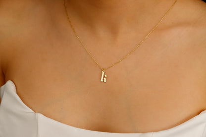 A close-up image of a woman wearing a sterling silver necklace with a gothic style initial pendant.