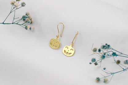 Gold earrings on a light gray background with small flowers.