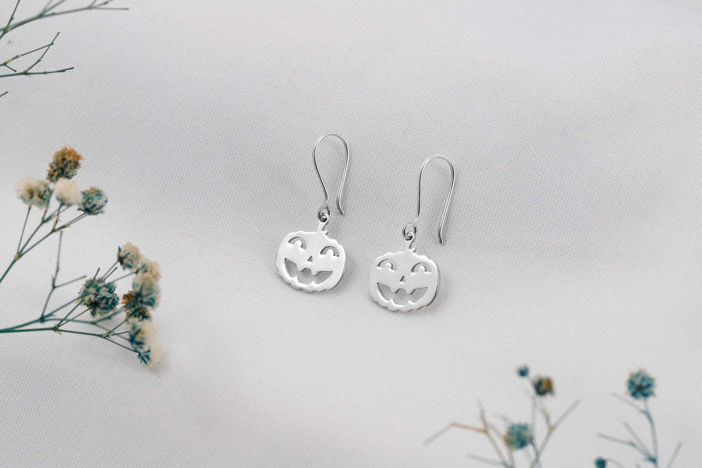 Silver earrings on a light gray background with small flowers.