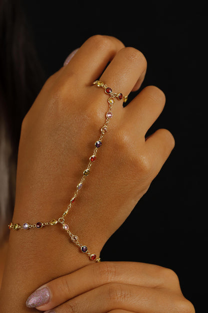 A person wearing a multicolored gemstone hand chain bracelet.
