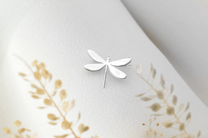 A dainty dragonfly brooch in silver color, attached to a piece of clothing.