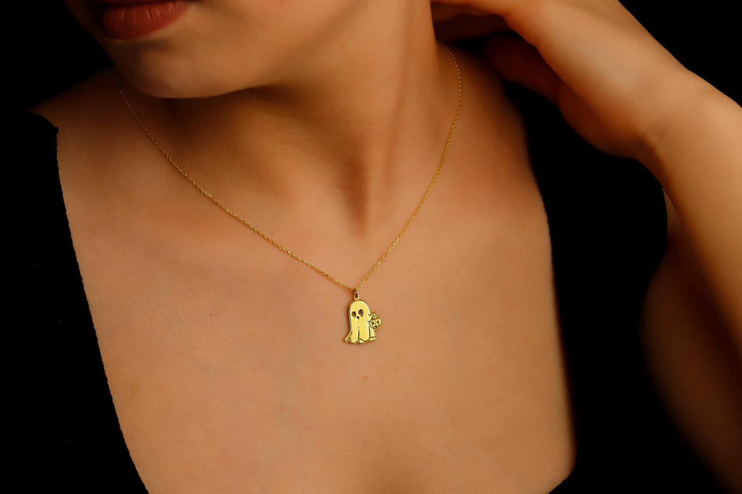 Gold necklace with a small pendant on a person wearing a black top.