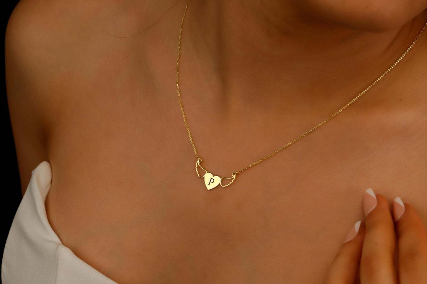 Gold necklace with a heart-shaped pendant on a person's neck