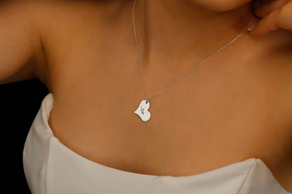 Necklace with a heart-shaped pendant worn by a person against a neutral background