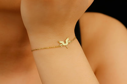 A bracelet with a 14K gold charm in the shape of a phoenix bird, displayed on a person's wrist.