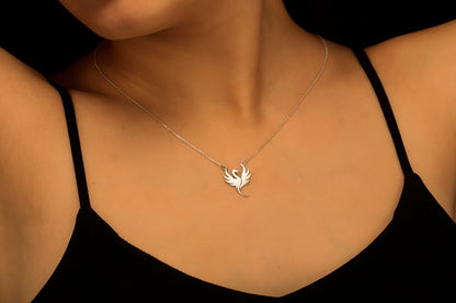 A person wearing a black tank top showcasing a silver necklace with a dragon charm.