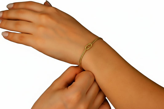 Gold bracelet on a wrist with a dark background