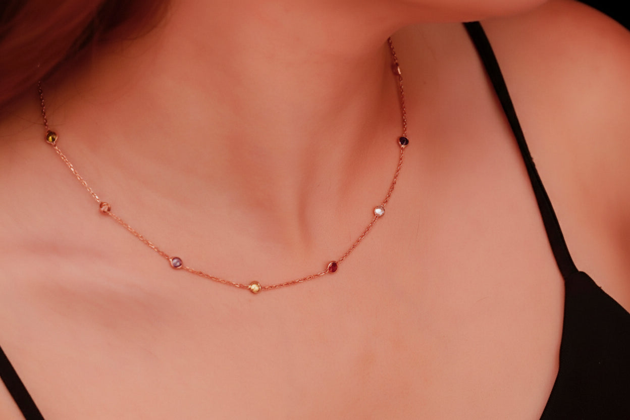 Close-up of a delicate necklace with small beads on a person wearing a black top.