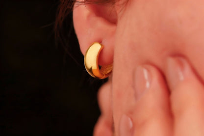 Close-up of a gold hoop earring worn on an ear with a blurred background