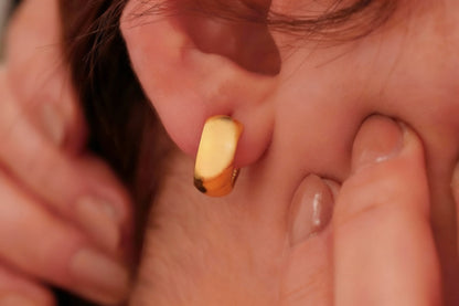 Close-up of a gold earring being worn.