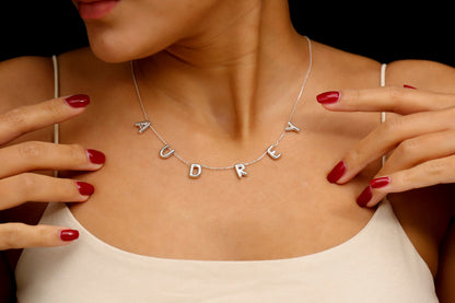 Necklace with 'AUDREY' pendant worn by a person with red nail polish.