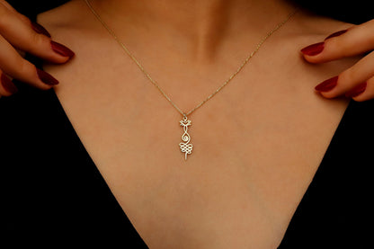Gold necklace with a leaf pendant on a person's neck against a black background