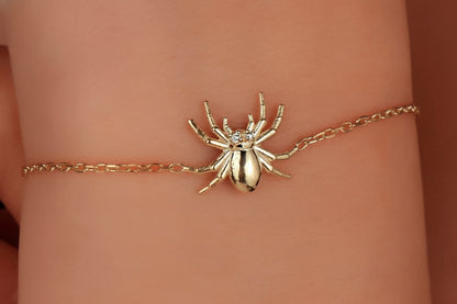 Gold spider bracelet on a wrist with a blurred background