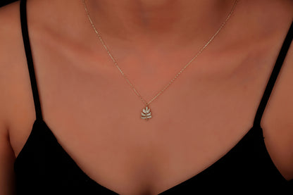 Necklace with a leaf pendant on a person wearing a black top.