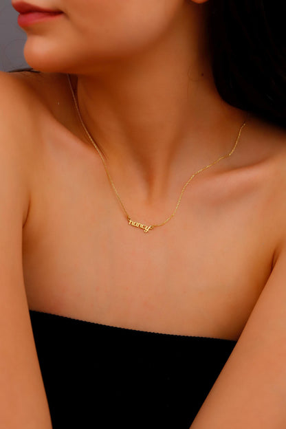 Gold necklace with 'lovey' pendant on a person wearing a black top.