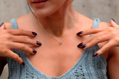 A woman wearing a delicate pink quartz, ametrine, and amethyst crystal choker necklace in silver tone.