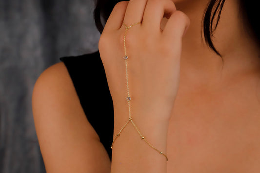 Gold body chain worn by a person against a neutral background