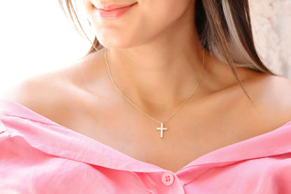A close-up image of a woman wearing a gold-filled, diamond cross necklace with a pendant cross on her neck.