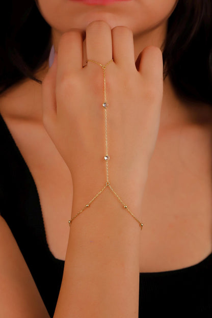 Gold hand chain worn on a hand with a blurred background