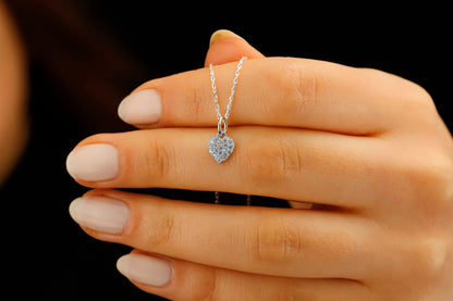 Heart-shaped diamond necklace on a hand against a black background