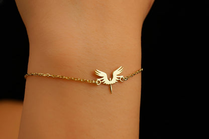 A bracelet with a 14K gold charm in the shape of a phoenix bird, displayed on a person's wrist.