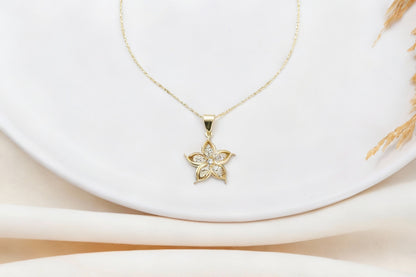A gold-filled necklace with a lily flower pendant, worn by a person.