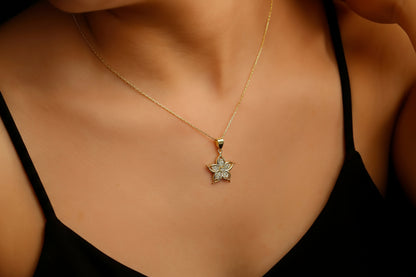 A gold-filled necklace with a lily flower pendant, worn by a person.