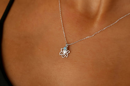 A close-up image of a person wearing a 14K gold filled necklace with a flower-shaped pendant.