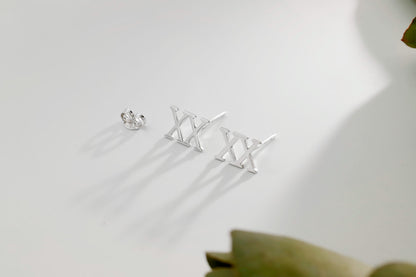 A close-up image of 3 stud earrings with the Roman numerals