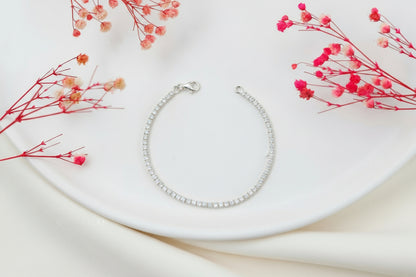 Silver tennis bracelet on a white plate with red flowers