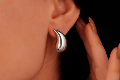 Silver earring worn by a person with a blurred background