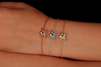 Three spider-shaped bracelets in different colors on a wrist against a black background