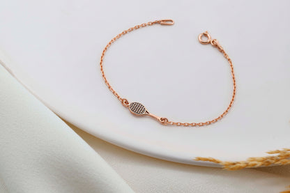 Rose gold bracelet on a white plate with a soft fabric background