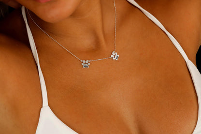 A close-up image of a person wearing a sterling silver paw-shaped necklace with a custom animal name pendant.