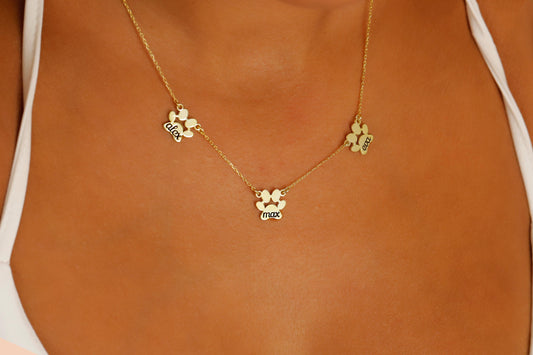 A close-up image of a person wearing a gold-filled paw-shaped necklace with a custom animal name pendant.