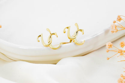 A close-up image of a man's hand holding a personalized cufflink with a monogram initial on it.