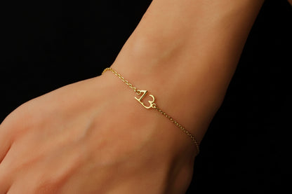 A person's wrist wearing a gold-colored bracelet with a specific number pendant.