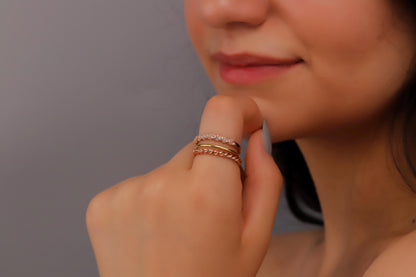 A person wearing a gold band twist ring on their pinky finger.