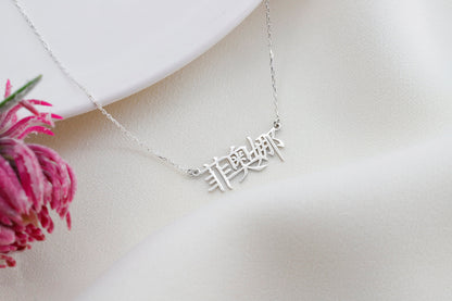 A close-up image of a woman wearing an silver pendant necklace with Chinese characters.