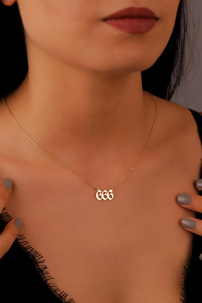A close-up image of a person wearing a gold necklace with the number 666 on it.