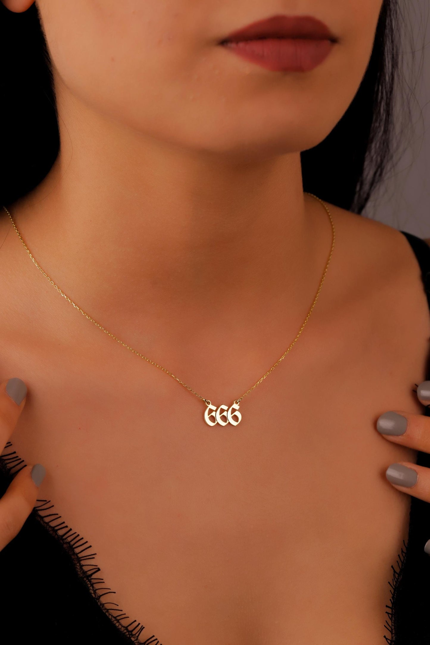 Gold necklace with initials worn by a person