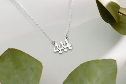 A close-up image of  a gold necklace with the number 444 on it.
