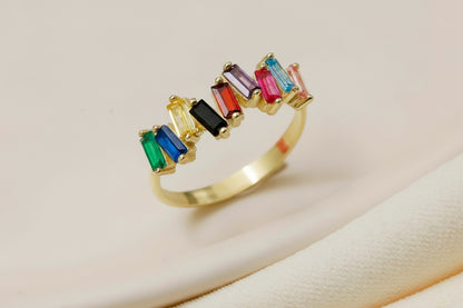 Gold ring with colorful gemstones on a beige background