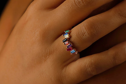 Multicolored gemstone ring on a hand against a dark background