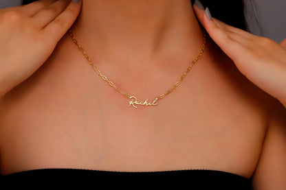 A woman wearing a dainty personalized name necklace in gold finish.