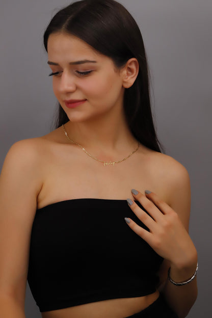 A woman wearing a dainty personalized name necklace in gold finish.